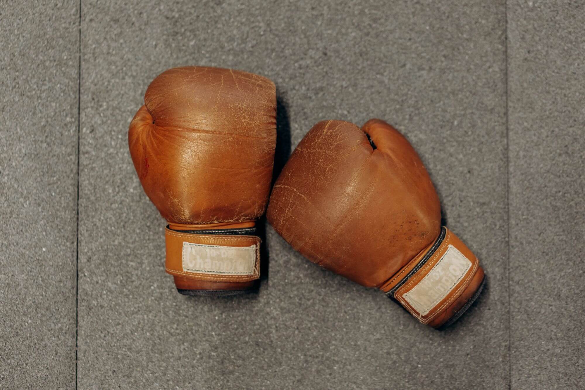 A pair of brown leather boxing gloves on gray surface