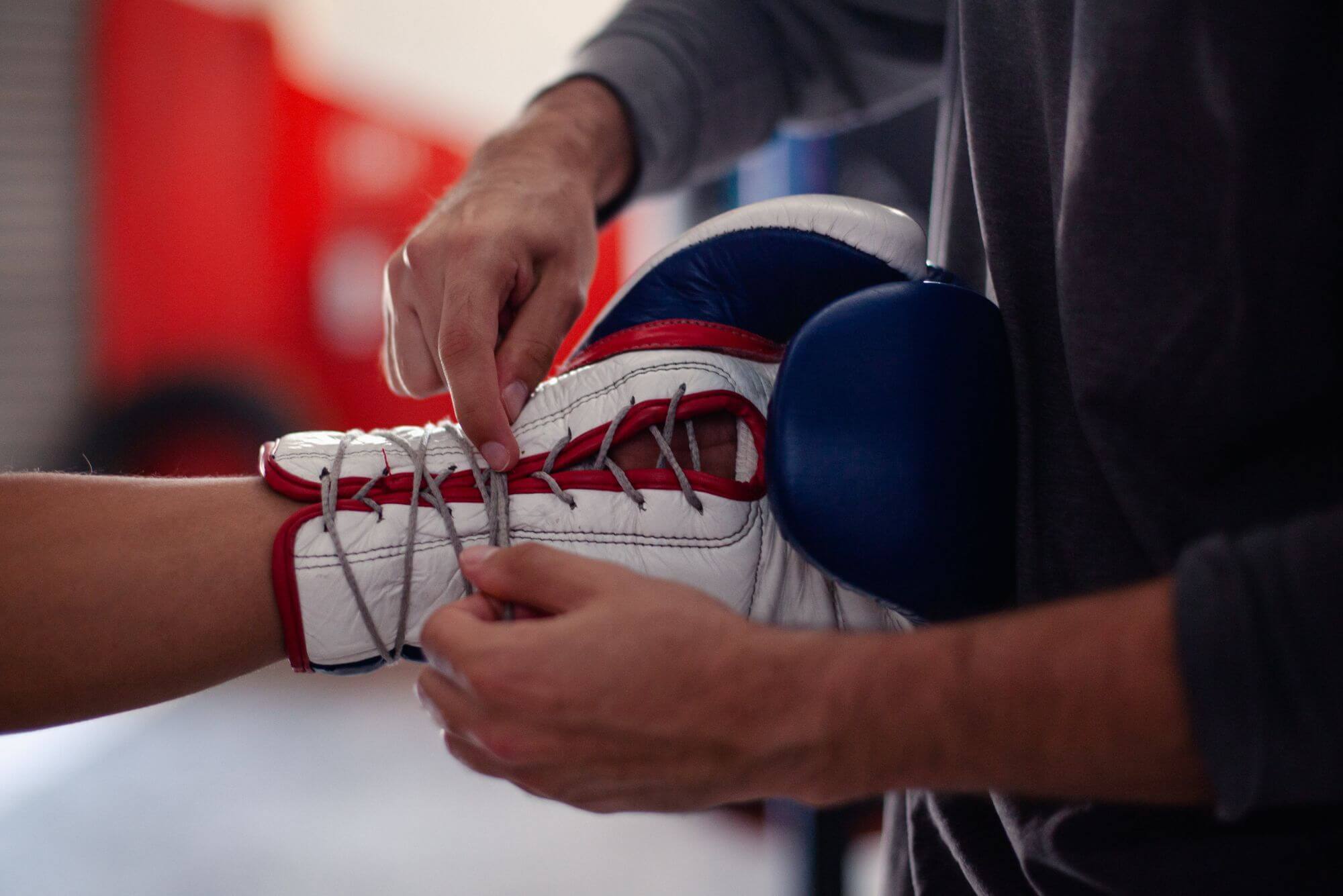 A person tying laces on a pair of boxing gloves in a boxing gym