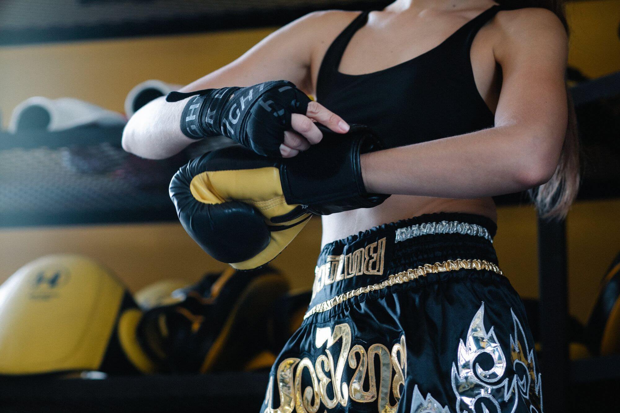 A white female boxer wearing black hand wraps before trying on a pair of boxing gloves